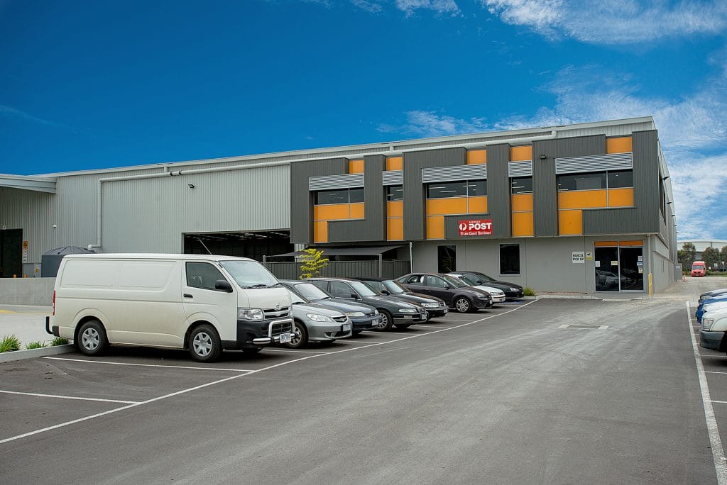 View of parking lot with vans with parcel handling facility in background