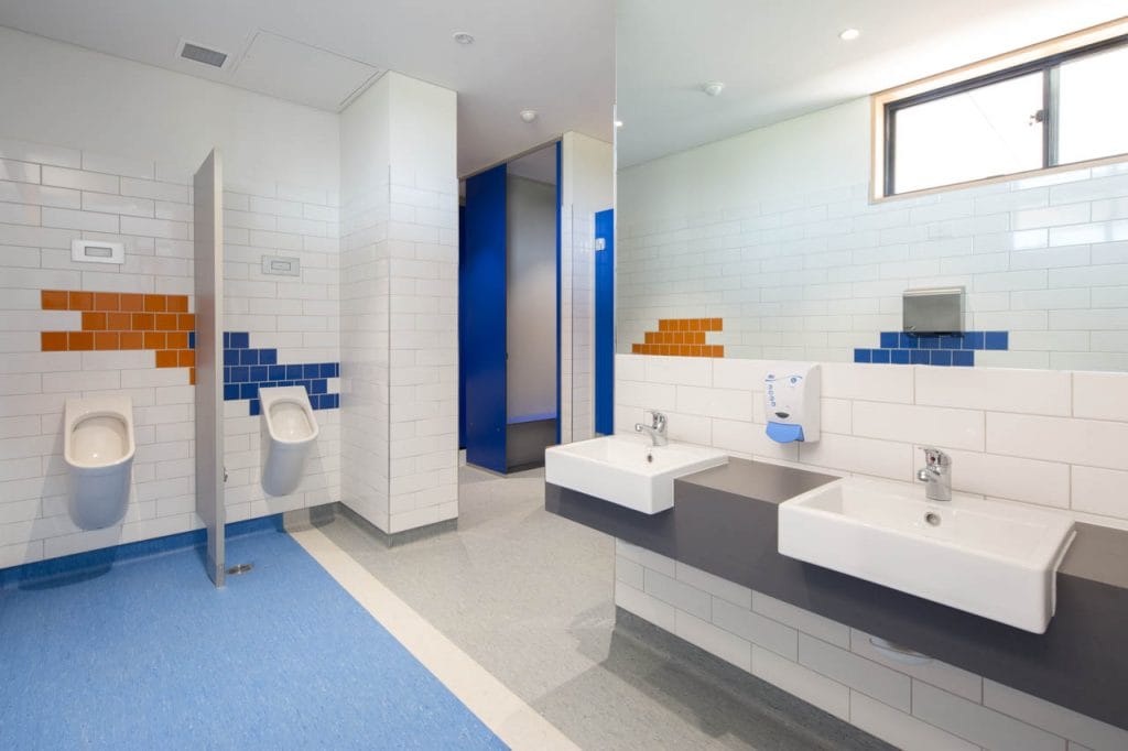 Boys toilet featuring orange and blue tiles