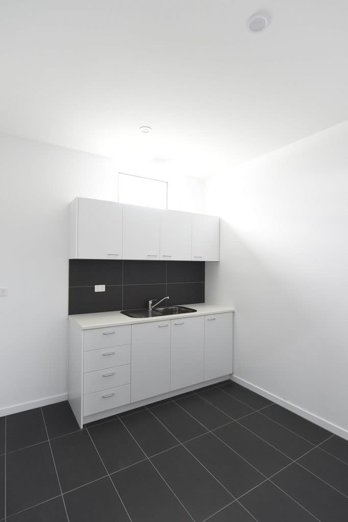 Kitchen area with grey floor tiles and black splash back