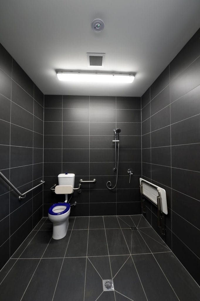 Disabled toilet facilities decorated with grey tiles on the floor and walls